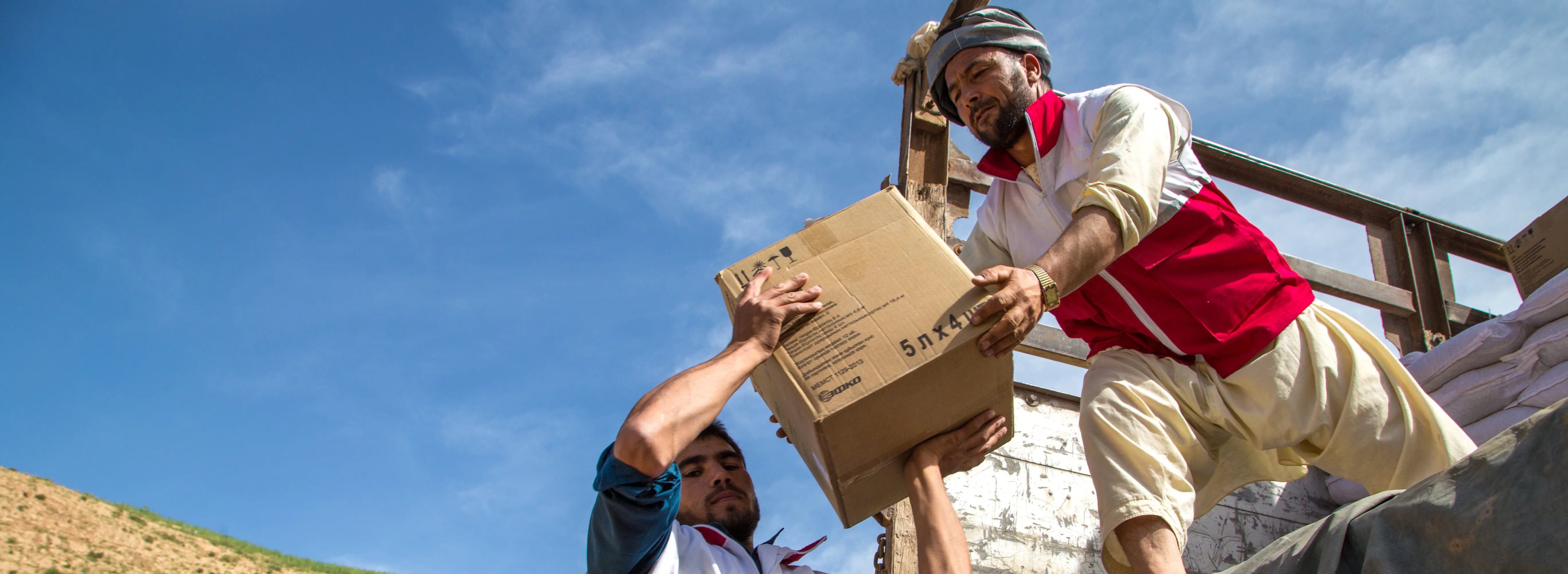 two men passing a box over to each other